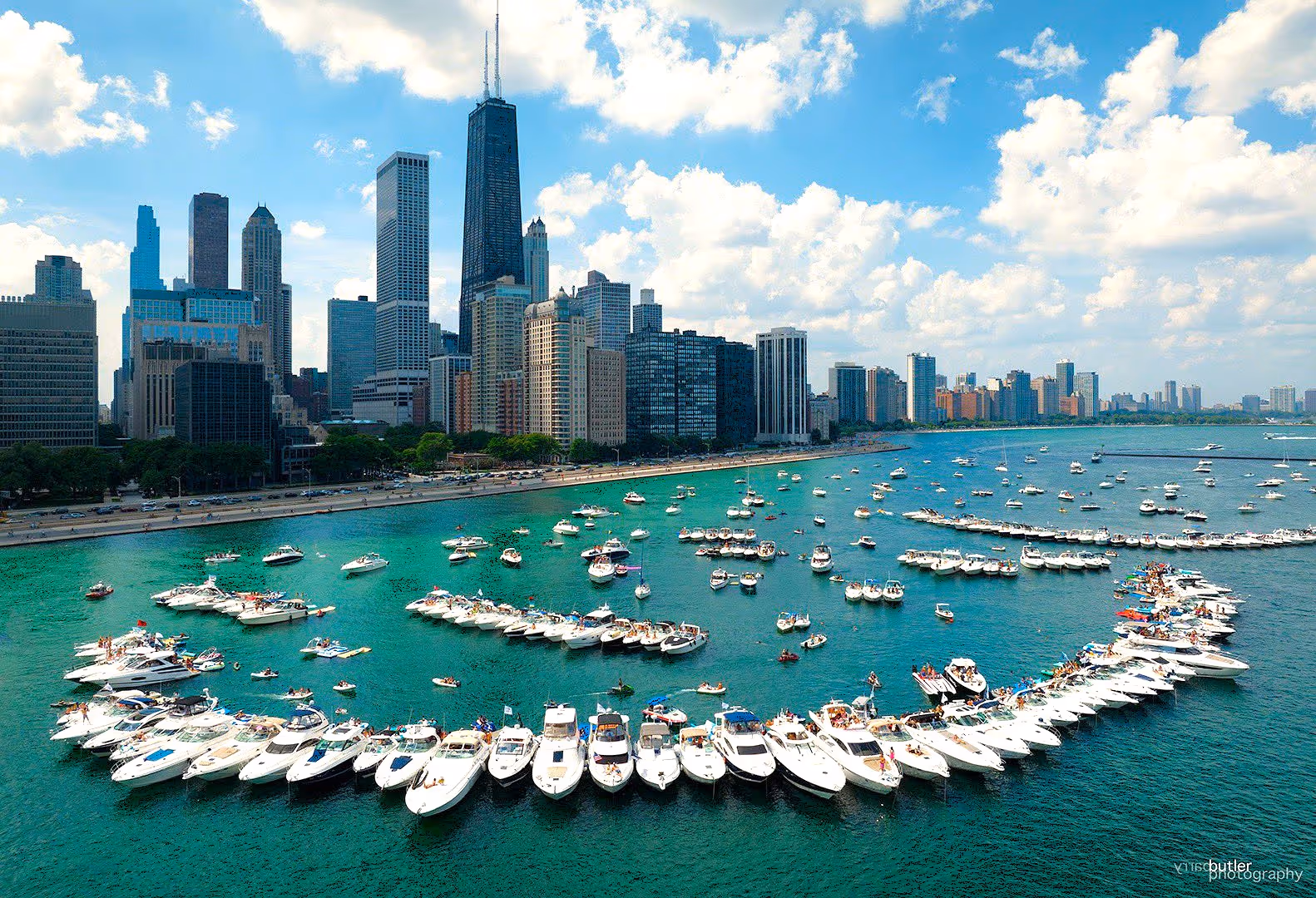 Yachts rafted up in a long curve at the Chicago Playpen with the Gold Coast skyline behind