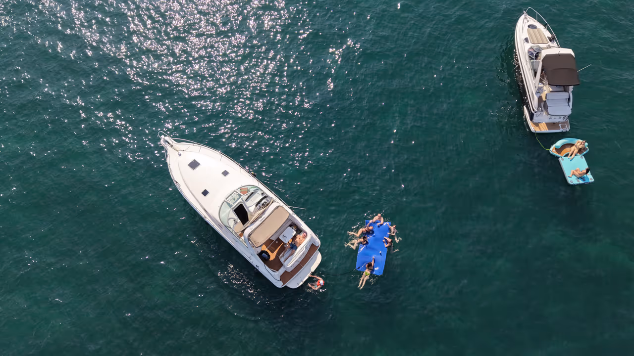Aerial view of a yacht anchored on Lake Michigan with guests floating on a lily pad mat beside the boat